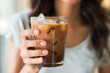 © Vilma - Woman's hand holding a Refreshing Iced Coffee in a Glass close up