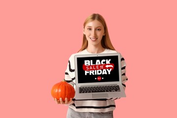 Canvas Print - Young woman with laptop and pumpkin on pink background. Black Friday sale