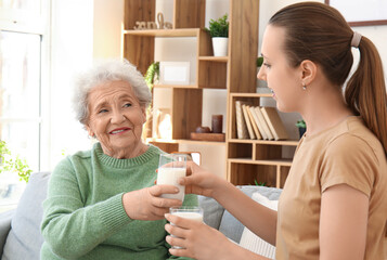 Canvas Print - Senior woman with her granddaughter drinking milk at home