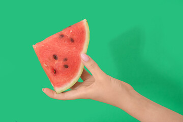 Wall Mural - Female hand with piece of ripe watermelon on green background, closeup