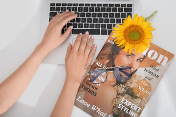 Sticker - Female hands with modern laptop, beautiful sunflower, eyeglasses and magazine on light background