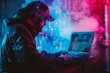 © Vitalii Shkurko - A hacker works on a laptop in a dark room filled with neon lights and smoke, representing cybersecurity threats.