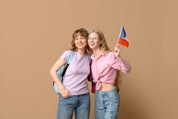 Wall Mural - Female students with French flags on beige background