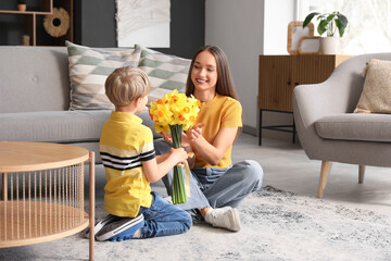 Wall Mural - Son greeting his happy mother with bouquet of beautiful narcissus at home