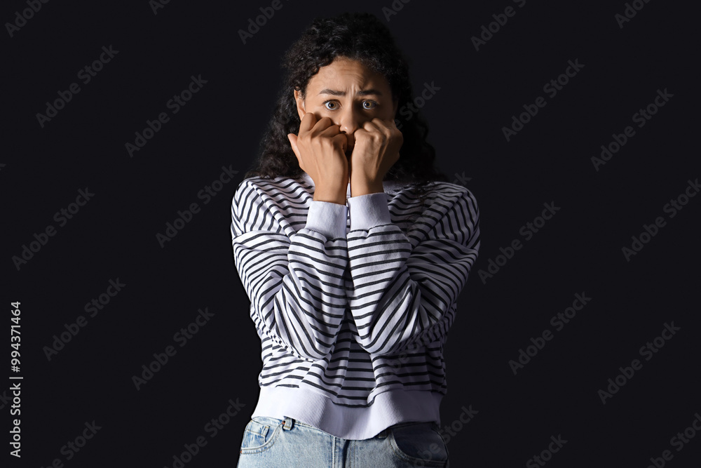 Young African-American woman having panic attack on black background