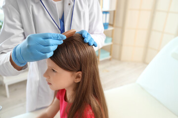 Poster - Female doctor combing little girl's hair in clinic, closeup. Pediculosis concept