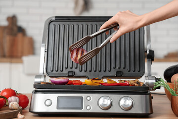 Wall Mural - Woman cooking vegetables on modern electric grill in kitchen