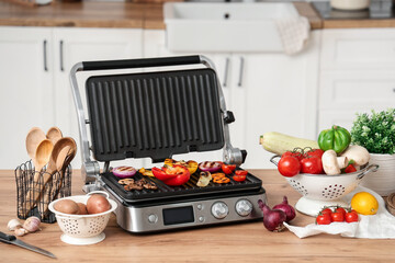 Tasty vegetables on modern electric grill on table in kitchen