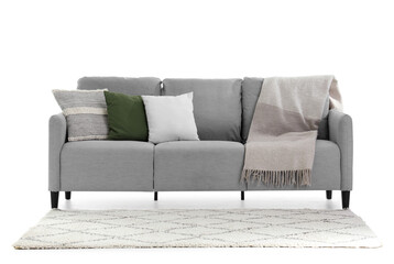 Wall Mural - Grey sofa with cushions, plaid and carpet on white background