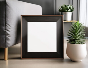 A black framed blank canvas mockup with a plant and a pot next to it against a minimal wall modern living room
