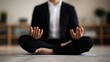 © angel_nt - A person sits cross-legged on a mat, hands raised in a meditative gesture, wearing formal clothing in a tranquil indoor setting, promoting peace and mindfulness
