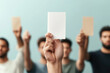 © NILSEN Studio - A focused hand holds up a blank card, with the blurred figures of people holding cards in the background against a muted blue wall.