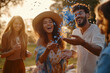 © Bonsales - Friends celebrating outdoors with blue confetti, wearing casual outfits, sunny day, joy and happiness concept
