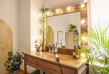 Canvas Print - Makeup table with glowing mirror, cosmetics and hair styler in dressing room