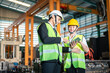 © Garun Studios - technician, safety, industrial, distribution, manufacturing, discussion, foreman, facility, warehouse, hard hat. Two men in safety gear are looking at a tablet. One of them is smiling.