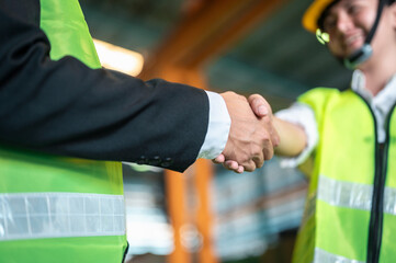 meeting, partner, plan, shake, renovation, agreement, deal, collaboration, foreman, handshake. Two men shake hands in a business meeting. One of them is wearing a green vest.