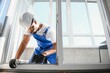© Serhii - African handyman adjusting white pvc plastic window indoors. worker using screwdriver to repair upvc window.