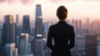© Maksym - The back view of a female CEO in formal wear, standing at the top of a high-rise building, looking out over the cityscape, her posture confident as she surveys the urban landscape