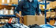 © LukaszDesign - Entrepreneur preparing clothing for export in a delivery box, focusing on retail, e-commerce shipping, and dropshipping in the fashion supply chain