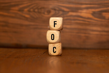 The word FOC written on wood cube. FOC - short for Free of charge.