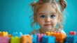 © fourtakig - Portrait of a cheerful child playing with toys on a plain, sky blue background with copy space