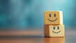 © Tati - Two wooden blocks with smiling faces stacked on table blue background