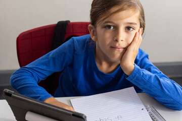 Wall Mural - In school, boy using tablet and writing in notepad, looking at camera