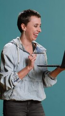 Wall Mural - Vertical video Trendy cool woman waving on a videocall connection in studio, using her laptop to attend an online remote meeting. Friendly person chatting on video conference call. Camera B.