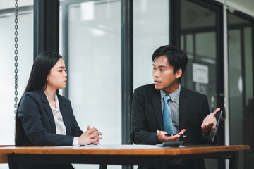 Two business professionals engaged in a serious discussion at a modern office table, emphasizing teamwork and collaboration.