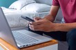© fadfebrian - Man working in his bedroom with a smartphone and laptop. Working from home, working on holiday or working from anywhere concept.