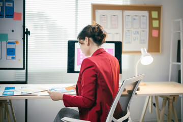 Ui/ux designer is analyzing mobile application wireframes at her desk. She is working on a design system for a new app