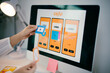 © Parichat - Female ux ui designer is working on a user experience for a mobile application, creating a wireframe with sticky notes on a computer screen