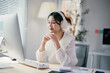 © Parichat - Focused asian businesswoman working at desk with computer in modern office, analyzing data and charts. Professional and determined
