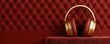 © Panisara - A luxurious pair of gold-accented red headphones rests against a textured red wall, showcasing a modern and elegant design.