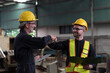 © amorn - Two male engineer join hands together in industry factory. Finished, completed work concept