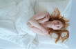 © ullision - Sexy redhead woman lies in bed, wrapped in white bedding, her arms gently crossed over her chest. Her relaxed expression and soft gaze create a peaceful, intimate, and serene atmosphere