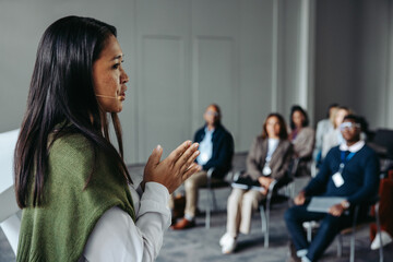 Confident female speaker leading a seminar with an engaged audience in a professional conference setting