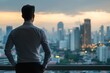 © Boinah - A man gazes at a city skyline during sunset, reflecting on his surroundings.