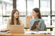 © aekachai - Asian businesswoman using a tapered laptop, sitting and talking in the office