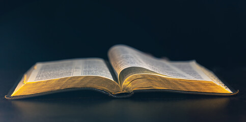 Open Bible on a black background. Religion concept.