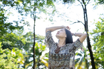 Young woman stretches her arms to receive freshness from the quiet nature. The concept of caring for the environment to help save the world. Fresh air, no pollution in the atmosphere, pure feeling.