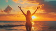 A woman with arms outstretched, enjoying a vibrant sunset over the ocean.