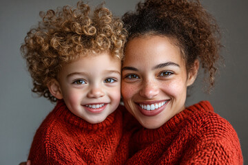 Wall Mural - Mixed racial young mother and cute daughter smiling and interacting in front of a plain background, dressed in simple  clothes, captured in a family photo portrait shoot showcasing their joyful bond