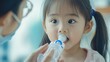© Nathan - A young Asian girl curiously drinking from a bottle, while being guided by an adult wearing glasses and a mask.
