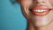 ©  Shomixer - A close-up of a bright smile featuring perfect white teeth and vibrant orange lips, presenting a cheerful and positive expression against a blue background.