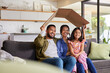 © Rido - Happy multiethnic family holding cardboard roof for new home