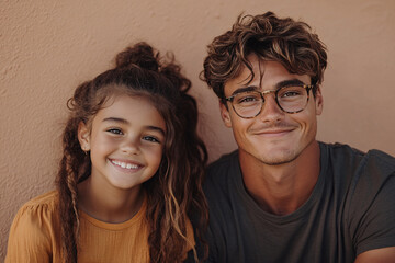 Wall Mural - Mixed racial Father and cute daughter smiling and interacting in front of a plain background, dressed in simple clothes, captured in a family photo portrait shoot showcasing their joyful bond