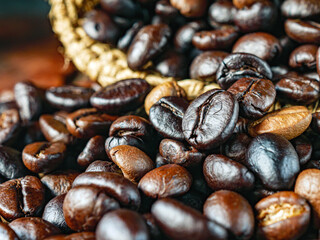 Roasted coffee beans poured out of a brown sack, close up of roasted coffee beans