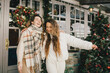 © polinaloves - Two women friends walking on festive decorated city street, having fun together.