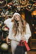 © polinaloves - Young beautiful womam enjoying Christmas shopping on a decorated street.